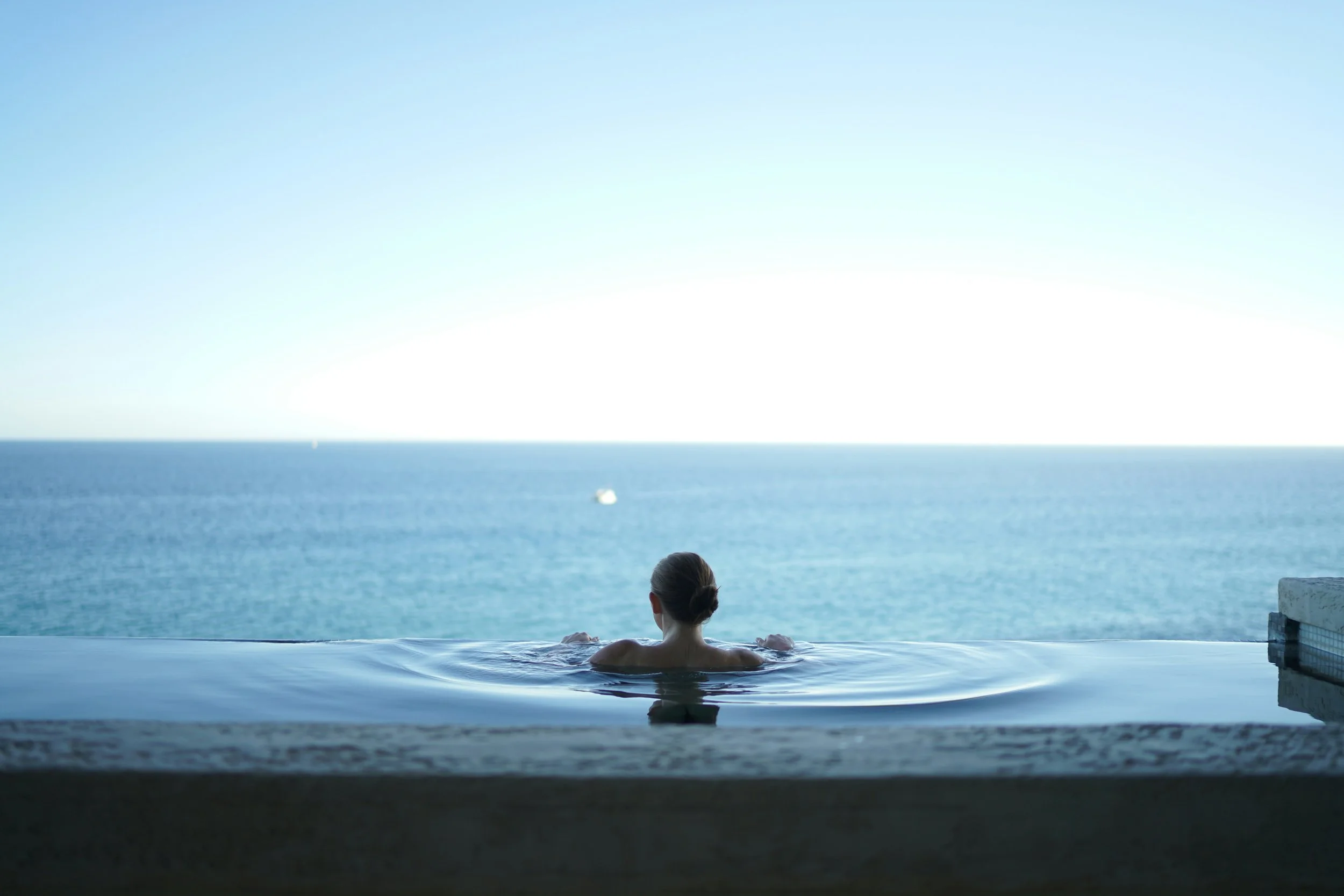 A person resting in an infinity pool overlooking the ocean